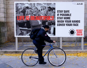 A man wearing a face mask bicycles along Broad Street, Wednesday, Nov. 18, 2020, in Philadelphia. (AP Photo/Matt Slocum)