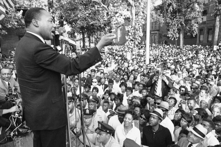 A line of police stands in front of a platform from which Dr. Martin Luther King speaks during a mass meeting in front of Girard College in Philadelphia on Aug. 4, 1965. Dr. King said the wall surrounding the school was a symbol of evil and called for continued efforts to integrate the school. (AP Photo)