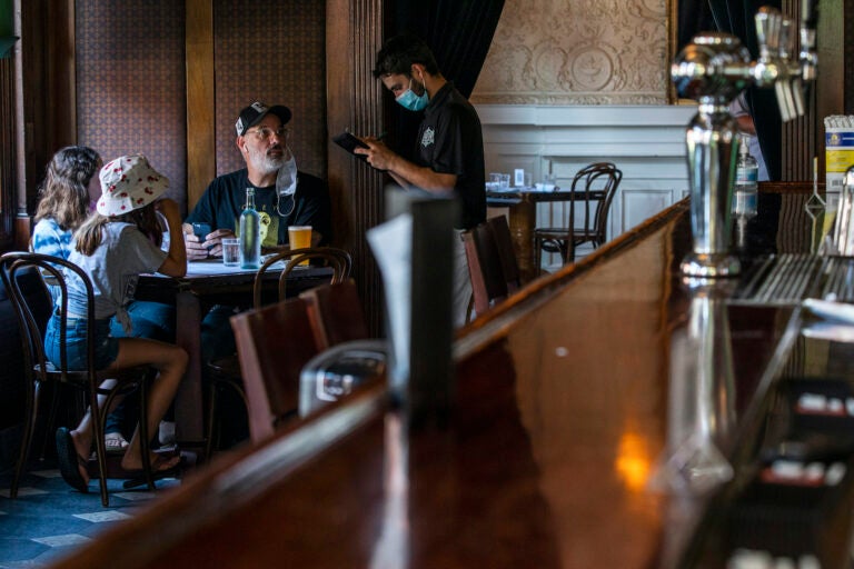 A waiter takes the order of customers inside a restaurant