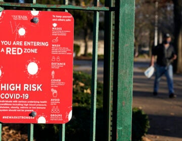 A sign at the entrance to a park warns pedestrians about increased risk for the coronavirus in the Ironbound section of Newark