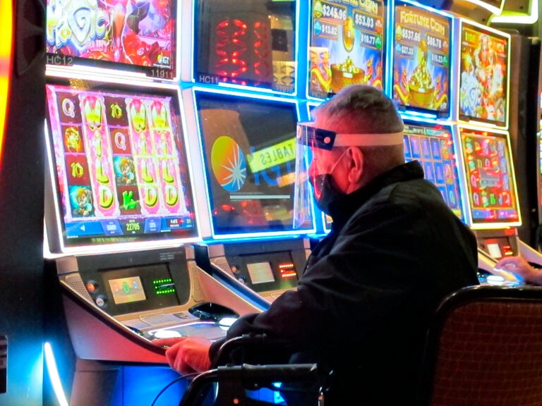 A man wears a face shield while playing a slot machine at the Golden Nugget casino