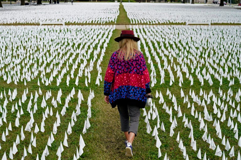 Artist Suzanne Brennan Firstenberg walks among thousands of white flags planted in remembrance of Americans who have died of COVID-19