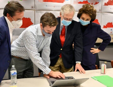 Republican Senate candidate Sen. Mitch McConnell, center, and his wife, Secretary of Transportation Elaine Chao, right, look on as aides show him the election results