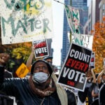 Zhanon Morales, 30, of Philadelphia, raises her fist as demonstrators call for all votes be counted outside the Pennsylvania Convention Center