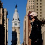 A woman wearing a face mask crosses Broad Street
