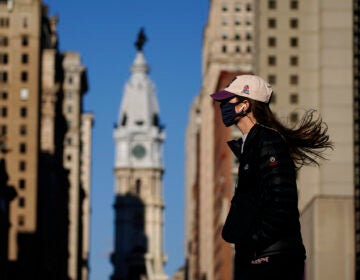 A woman wearing a face mask crosses Broad Street