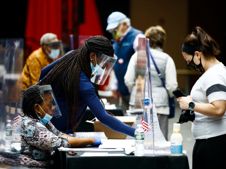Election workers, left, check in voters before they cast their ballots in the Pennsylvania primary in Philadelphia