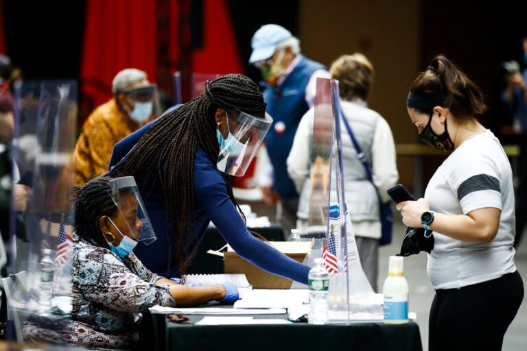 Election workers, left, check in voters before they cast their ballots in the Pennsylvania primary in Philadelphia