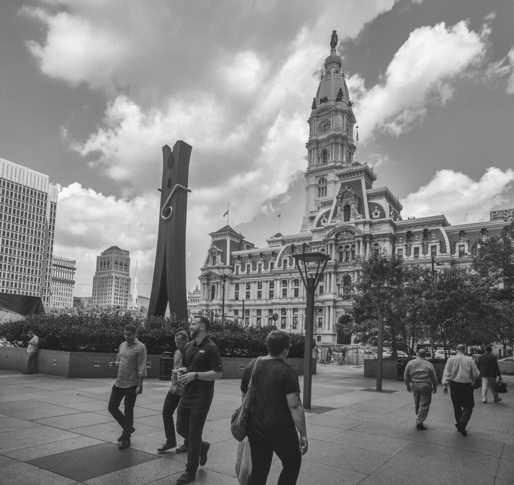 A black and white photo of the Clothespin with people walking by and City Hall in the background.