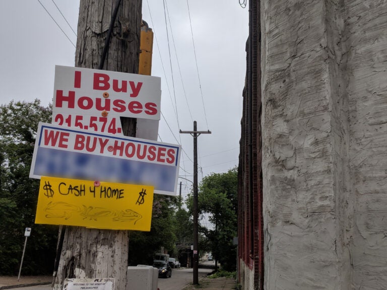 Signs that read, ''I Buy Houses'' and ''We Buy Houses'' can be seen posted on a street pole in Philly