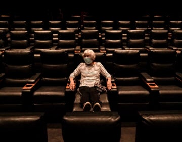 A woman sits in a theater in Irvine, Calif., waiting for a movie to start, on Sept. 8. A COVID-19 vaccine could unleash pent-up spending from households that have mostly avoided activities like going to the gym during the coronavirus pandemic. (Jae C. Hong/AP Photo)