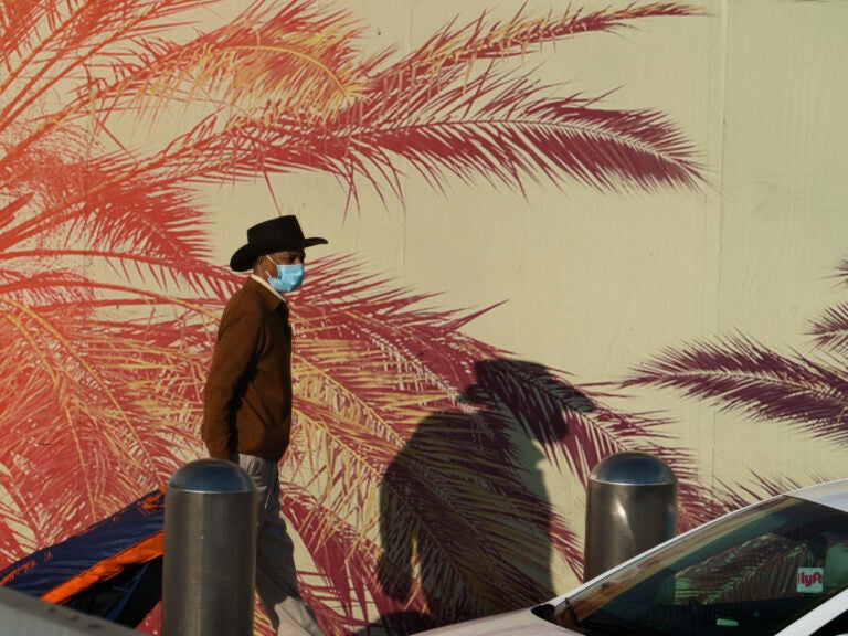 Travelers wear face masks at Los Angeles International Airport in Los Angeles on Friday. The U.S. is leading the world in confirmed coronavirus infections. (Damian Dovarganes/AP Photo)