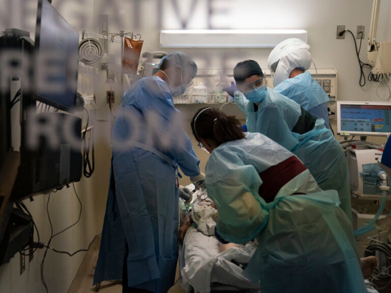 Health care workers treat a patient who tested positive for the coronavirus last week at Providence Holy Cross Medical Center in Los Angeles. California has imposed an overnight curfew on most residents as the most populous state tries to head off a surge in the coronavirus.