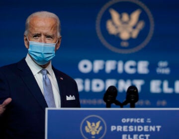 Joe Biden stands at a podium wearing a face mask