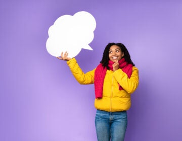 A cheerful Black woman holding an empty speech bubble above her head