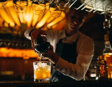 The Bartender Squeezes Citrus Juice Into A Cocktail.