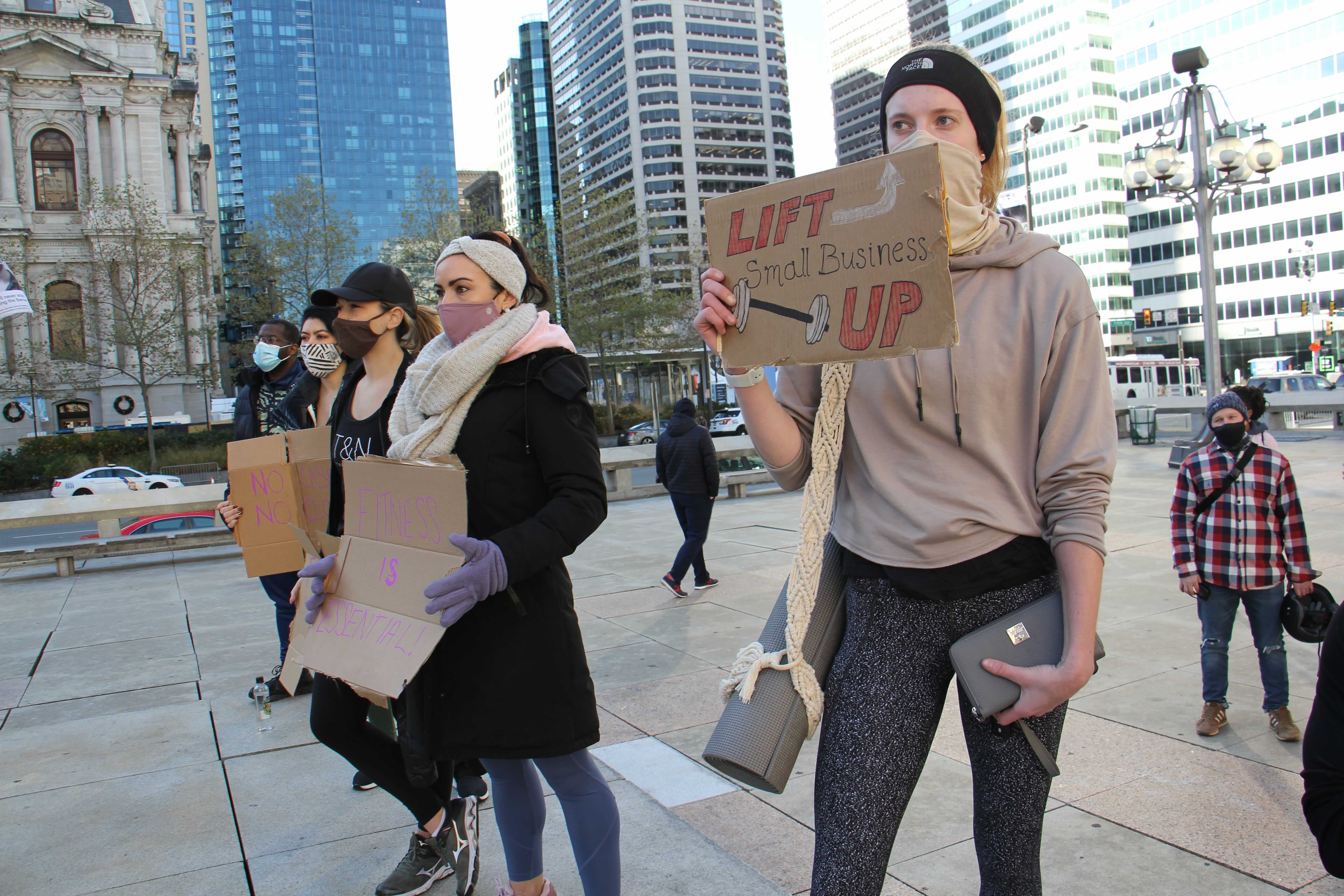 Protesters carry signs in support of gym owners who want to stay open despite the coronavirus pandemic.