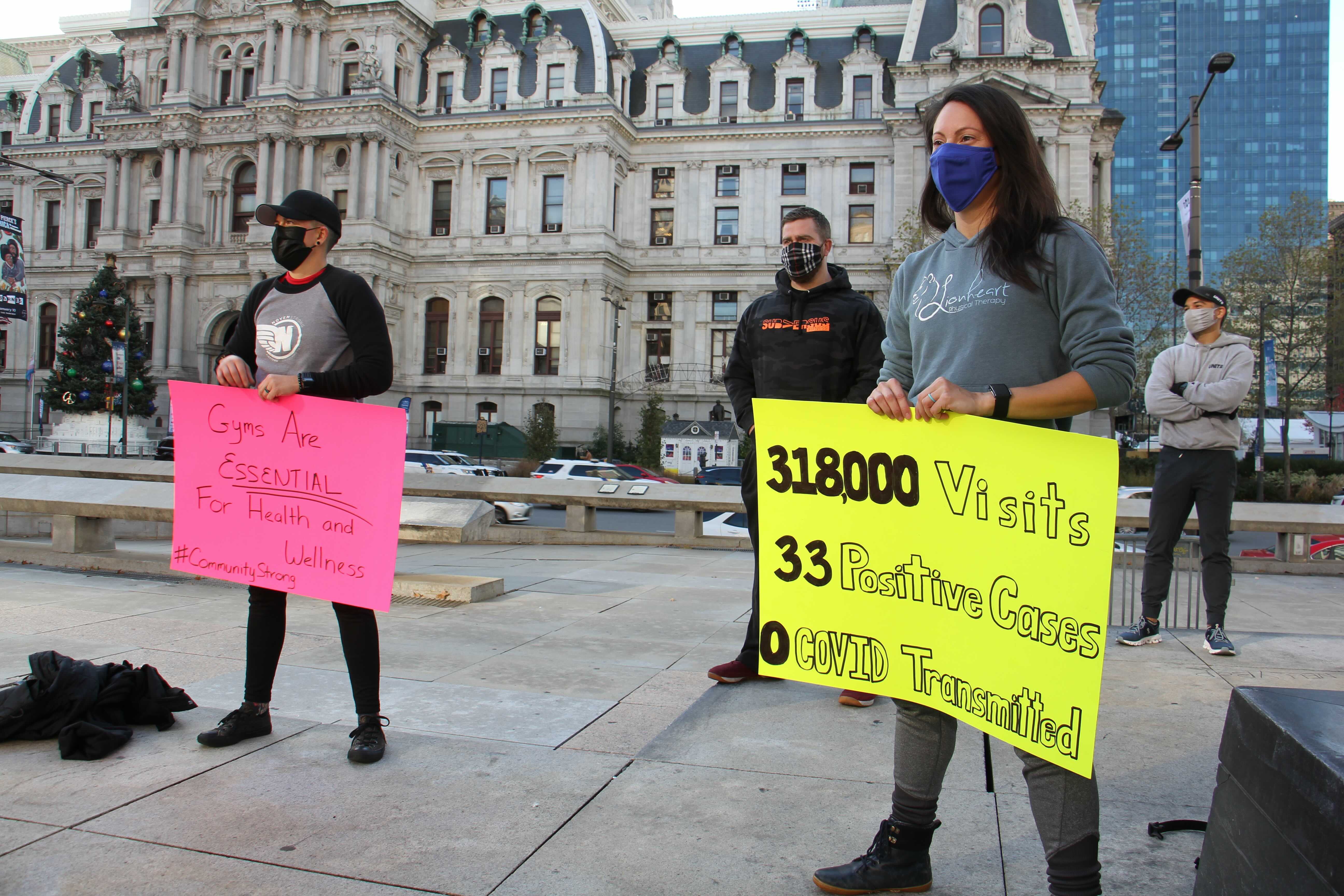 Protesters carry signs in support of gym owners who want to stay open despite the coronavirus pandemic.