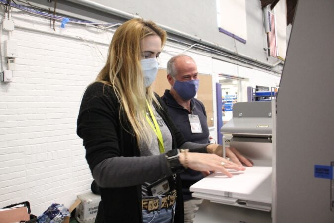 Chester County election workers Megan Delaney and David Turnier load ballots into a scanner at the West Chester University gym.