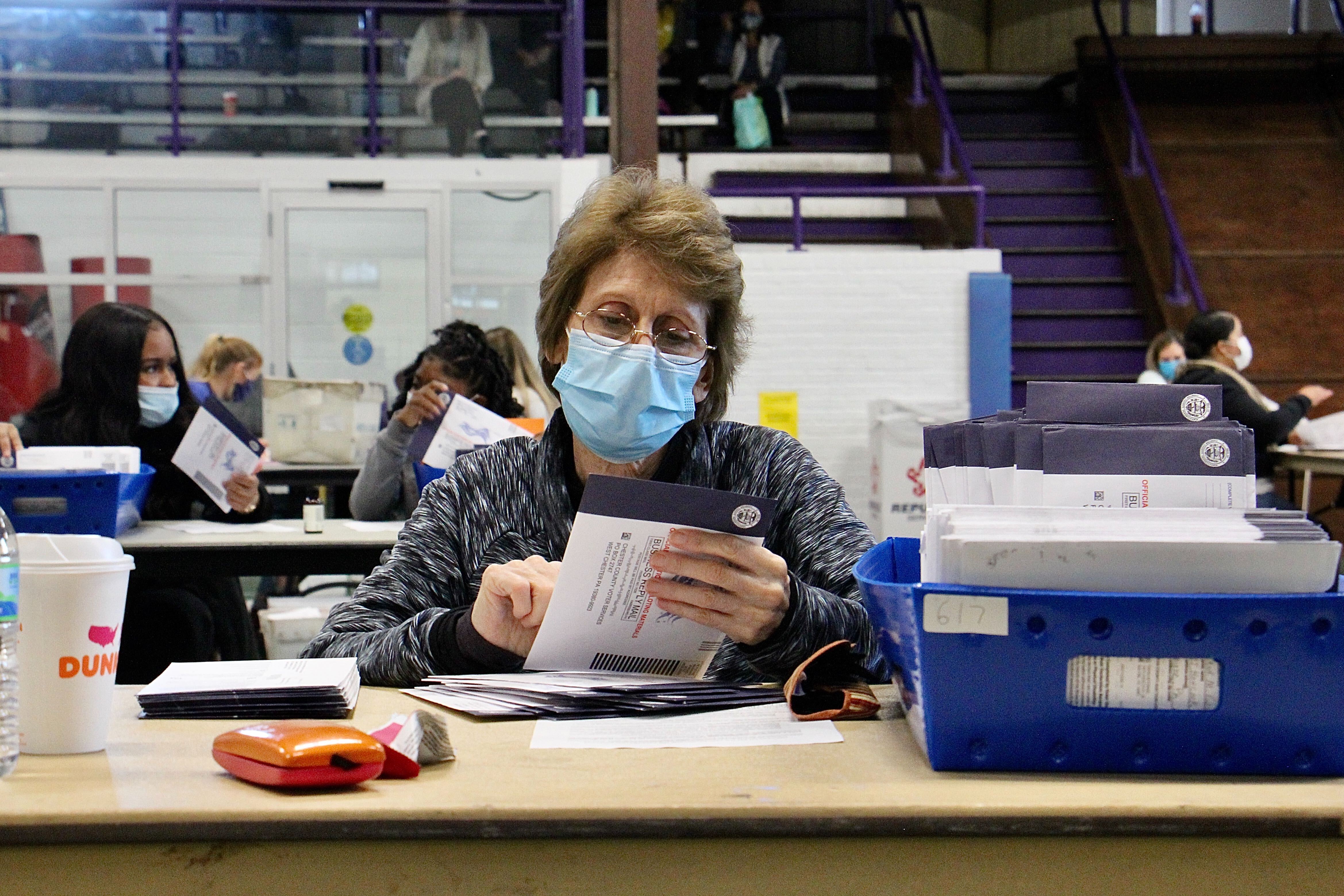 Election worker Patricia Masi inspects mail-in ballots at the West Chester University gym