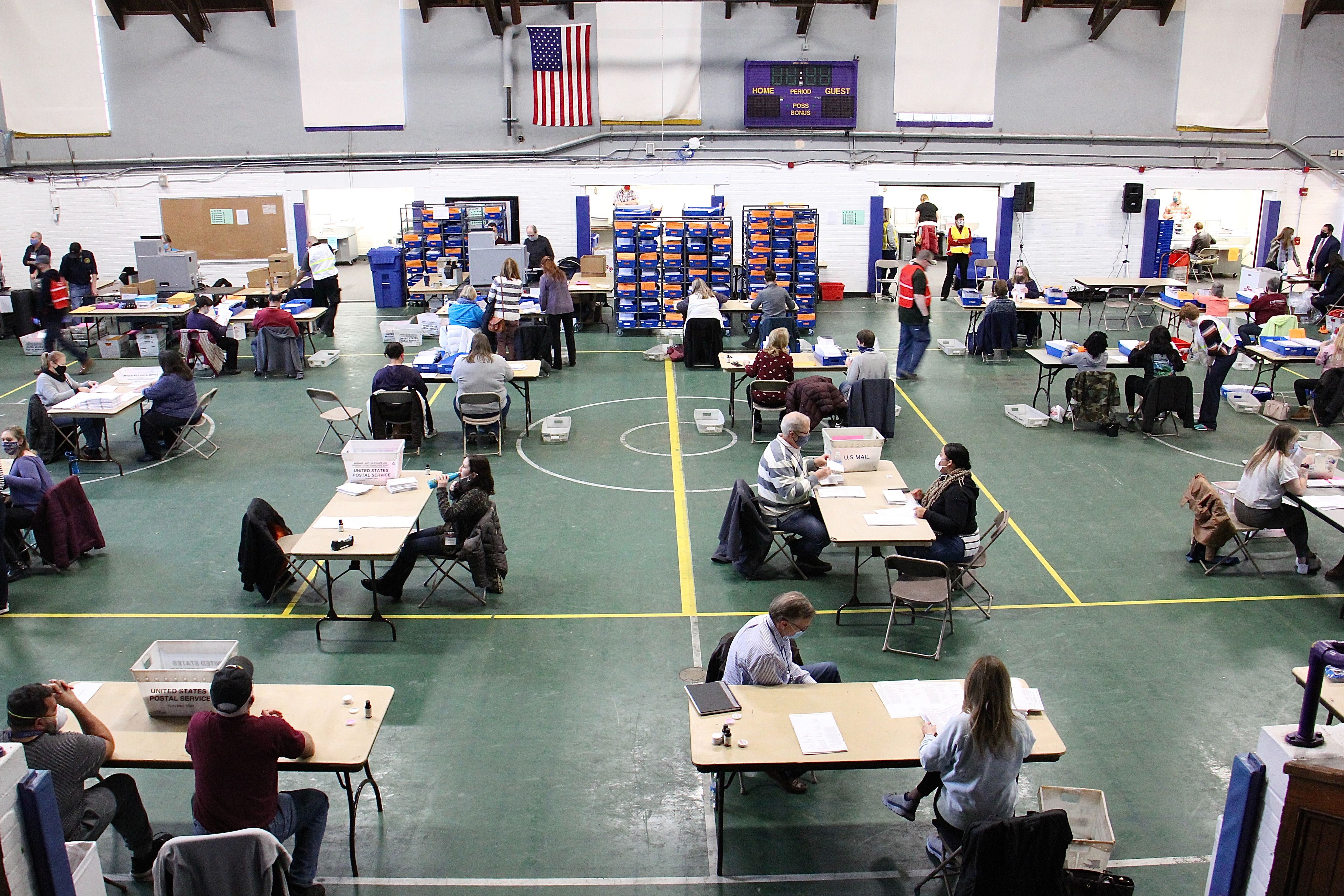 Chester County election workers sort, inspect, flatten and scan mail in ballots at the West Chester University gym.