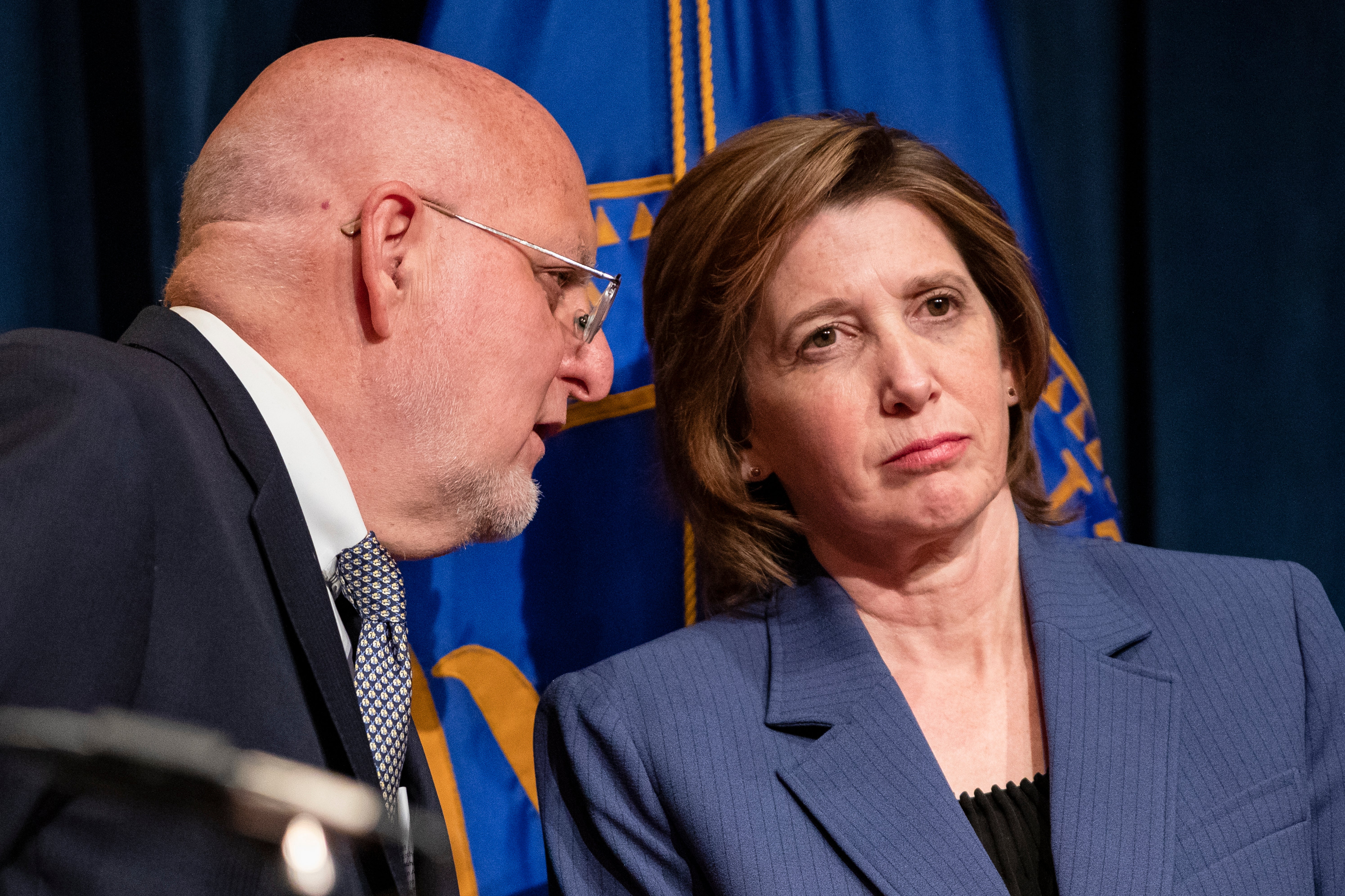 Centers for Disease Control and Prevention Director Robert Redfield whispers to National Center for Immunization and Respiratory Diseases Director Nancy Messonnier during a press conference