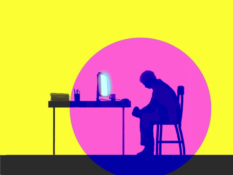 Depressed man sitting in front of glowing computer screen.