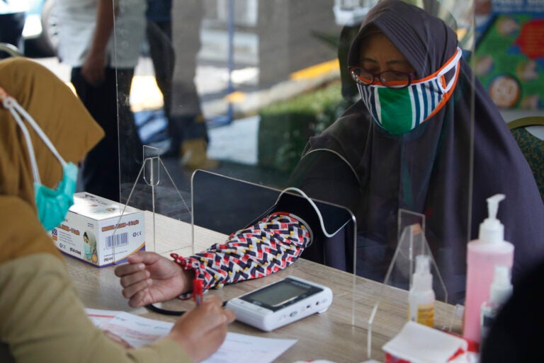 Health workers measure a woman's blood pressure during a simulation of a COVID-19 vaccine trial in Indonesia. (Adriana Adie/NurPhoto via Getty Images)