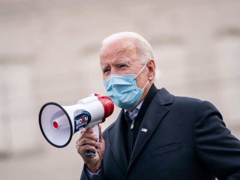 Joe Biden speaks with a megaphone in hand while masked