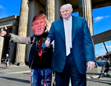 A supporter of President Trump's poses with a cardboard cutout likeness Wednesday in front of the Brandenburg Gate in Berlin. (John MacDougall/AFP via Getty Images)