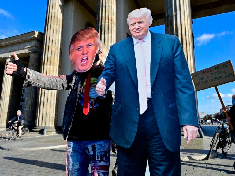 A supporter of President Trump's poses with a cardboard cutout likeness Wednesday in front of the Brandenburg Gate in Berlin. (John MacDougall/AFP via Getty Images)