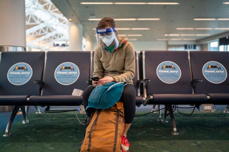 A traveler waits for a flight at Portland International Airport in Oregon last week. Public health experts say it's important that people who traveled or gathered with others are especially careful over the next two weeks. (Nathan Howard/Getty Images)
