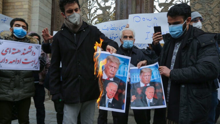Iranian protesters burn images of President Trump and President-elect Joe Biden during a rally Saturday in Tehran