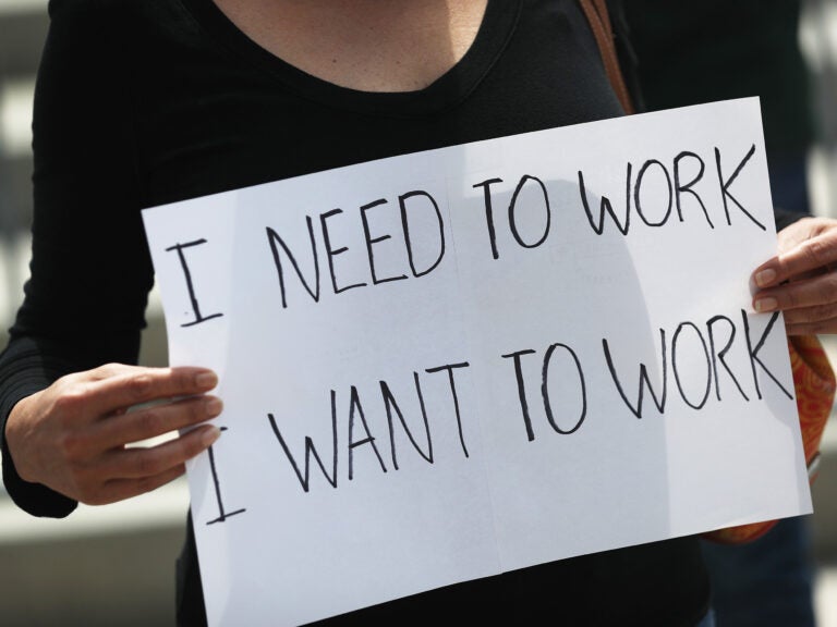 A protester holds a sign as she joins with restaurant owners, workers and supporters on July 10, 2020, to protest measures in Miami to close indoor seating amid a rise in coronavirus cases. The number of unemployment claims rose for a second week, reinforcing concerns about the economy. (Joe Raedle/Getty Images)