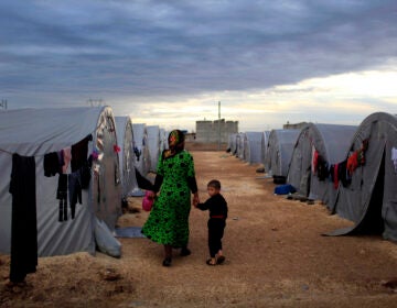 A Kurdish refugee mother and son from the Syrian town of Kobani walk beside their tent in a camp in the southeastern town of Suruc on the Turkish-Syrian border in 2014 in Sanliurfa, Turkey. President-elect Joe Biden aims to reverse the Trump administration's dramatic cuts to refugee admissions. (Gokhan Sahin/Getty Images)