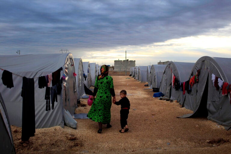 A Kurdish refugee mother and son from the Syrian town of Kobani walk beside their tent in a camp in the southeastern town of Suruc on the Turkish-Syrian border in 2014 in Sanliurfa, Turkey. President-elect Joe Biden aims to reverse the Trump administration's dramatic cuts to refugee admissions. (Gokhan Sahin/Getty Images)