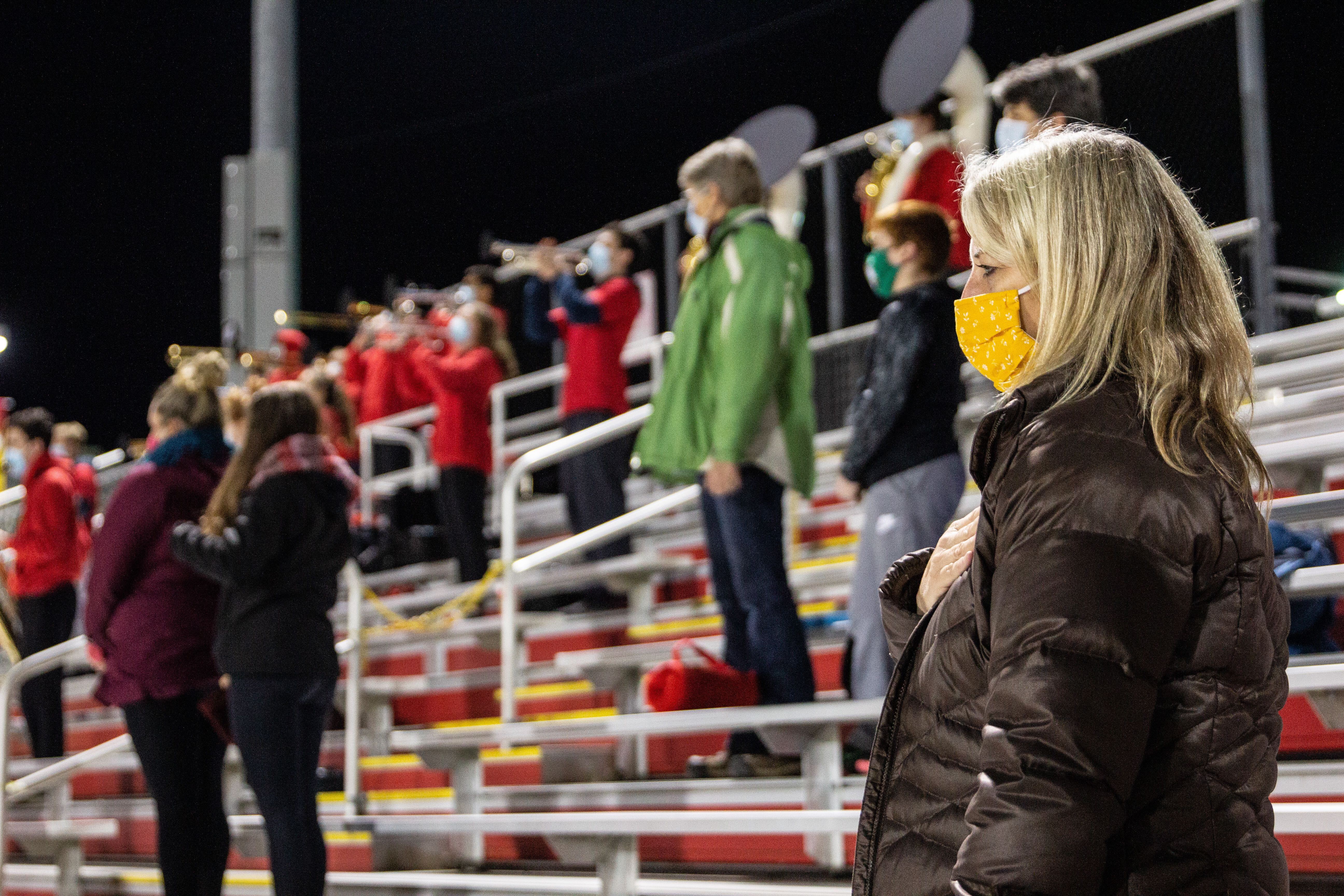 Masked and distanced parents of Penncrest High School football players stand for the national anthem before the Media Bowl.