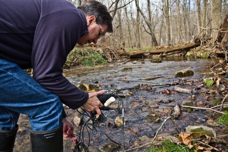 John Jackson, senior research scientist at the Stroud Water Research Center, measure conductivity in the White Clay Creek stream. (Kimberly Paynter/WHYY)