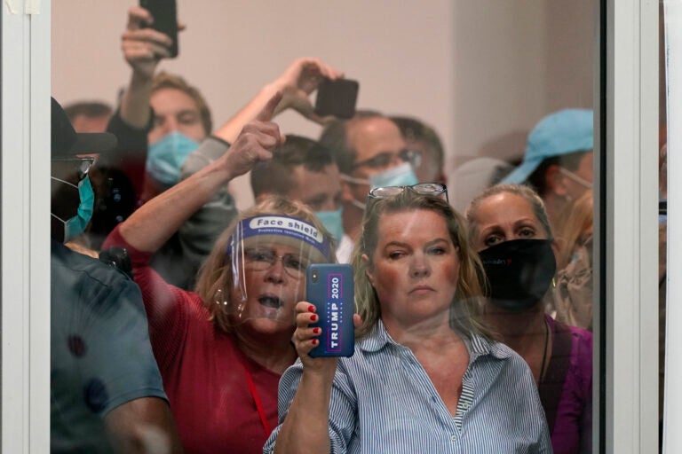 People wanting to be election challengers yell as they look through the windows of the central counting board as police were helping to keep additional challengers from entering due to overcrowding