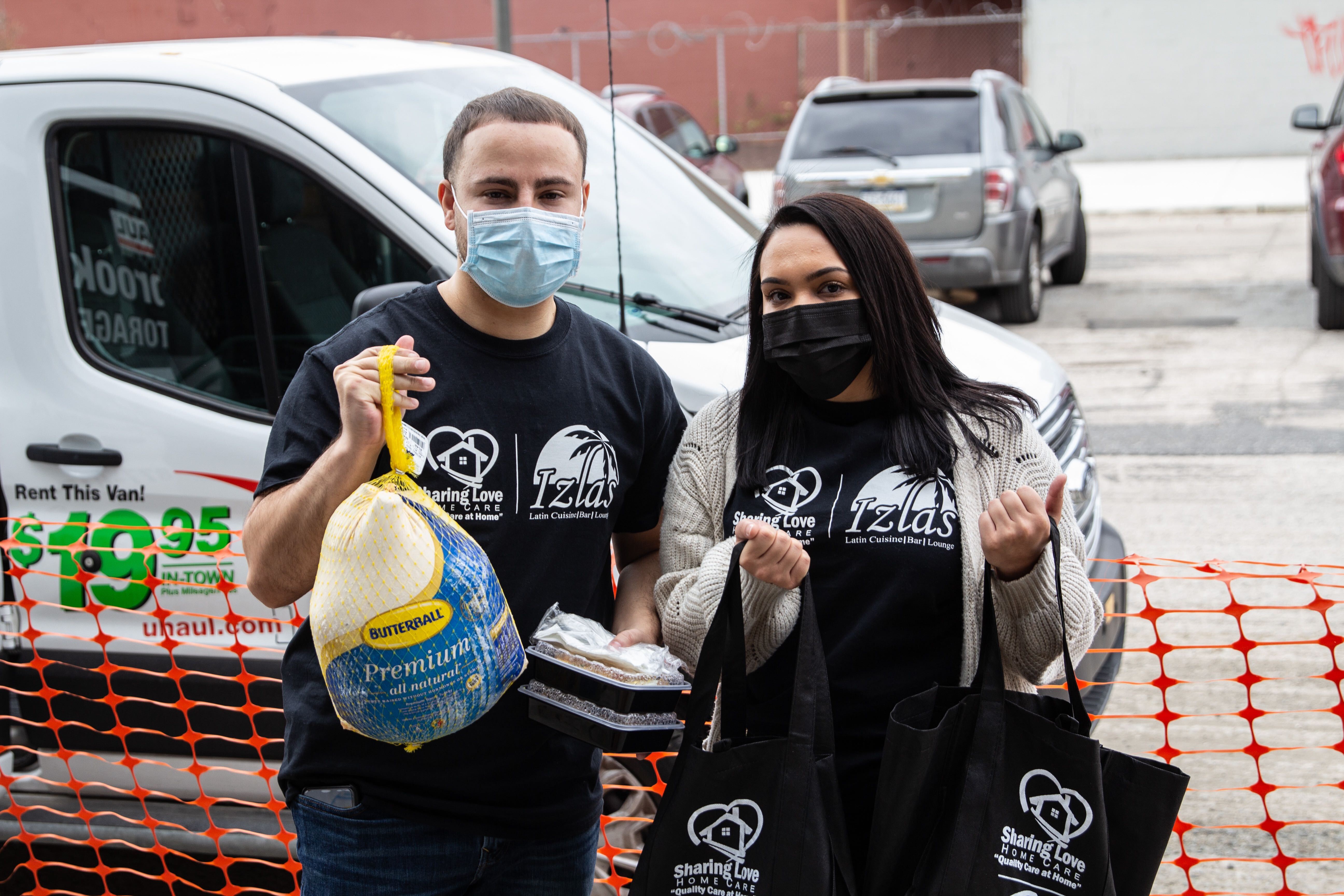 Ricardo Santana and Ashley Vargas hold a turkey during a giveaway event in Kensington