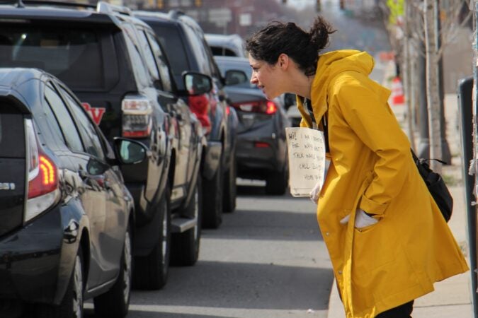 Nina Feldman talks with people lined up to use the city's first drive-through coronavirus testing site at Citizens Bank Park. (Emma Lee/WHYY)