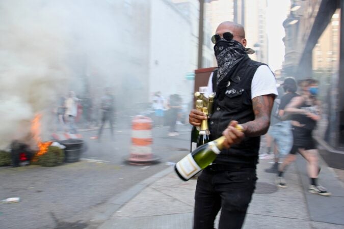 A looter leaves Marathon Grill at 16th and Sansom streets with an armload of champagne. (Emma Lee/WHYY)