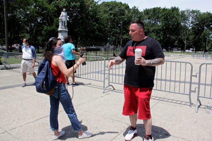 Katie Meyer asks John Florio why he is defending the Columbus statue at Marconi Plaza in South Philadelphia. (Emma Lee/WHYY)