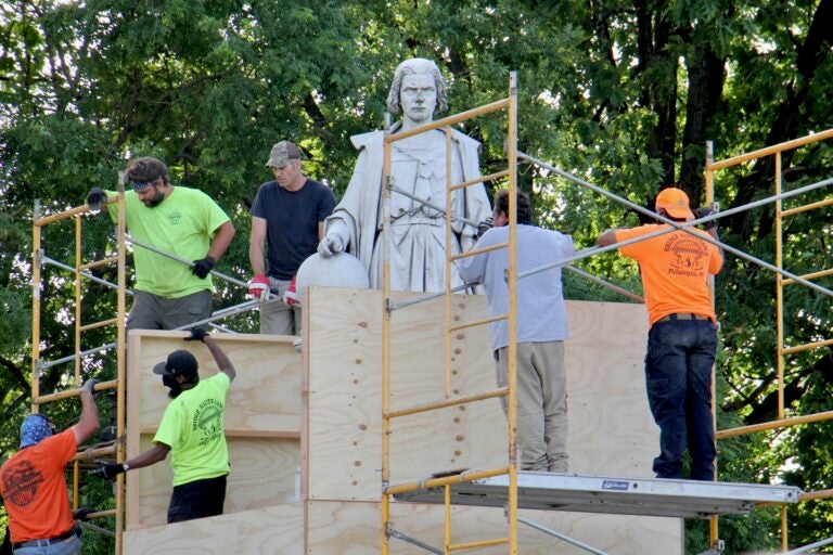 Workers box up the statue of Christopher Columbus at Marconi Plaza