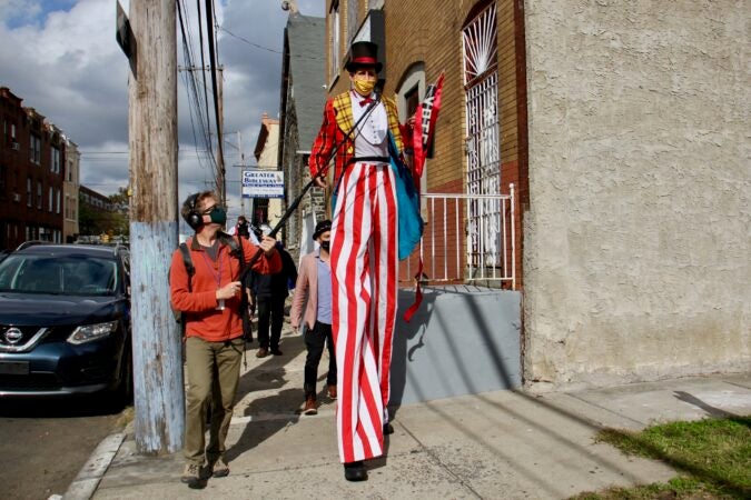 Peter Crimmins interviews a member of Cirque d'Vote as the group parades through North Philadelphia. (Emma Lee/WHYY)