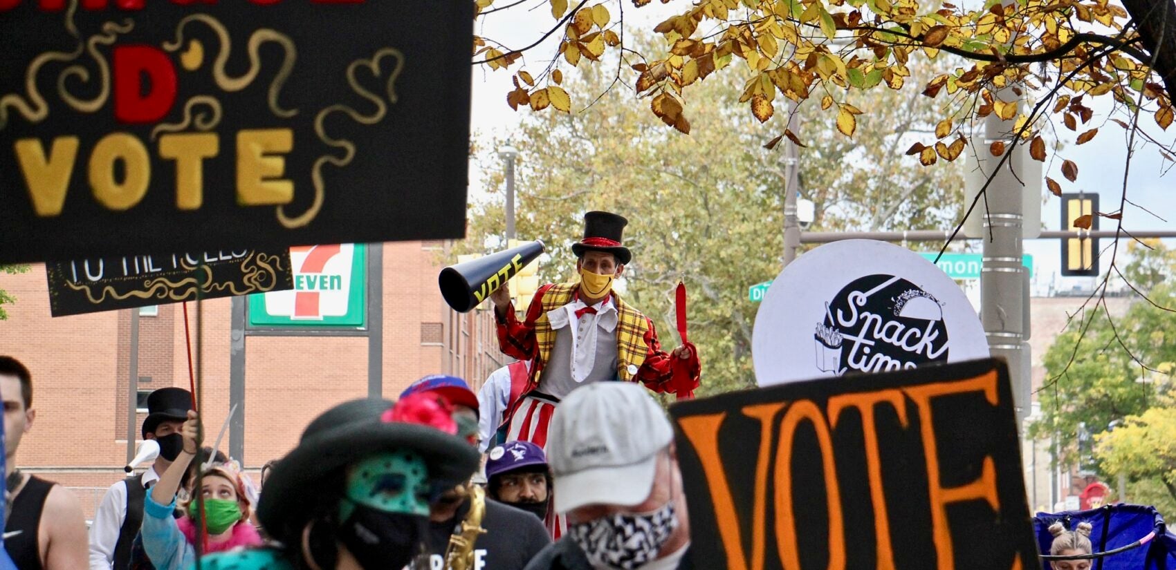 Cirque d'Vote performers make their way down North Broad Street toward the Liacouras Center, where their aim is to cheer the voters standing in line there. (Emma Lee/WHYY)