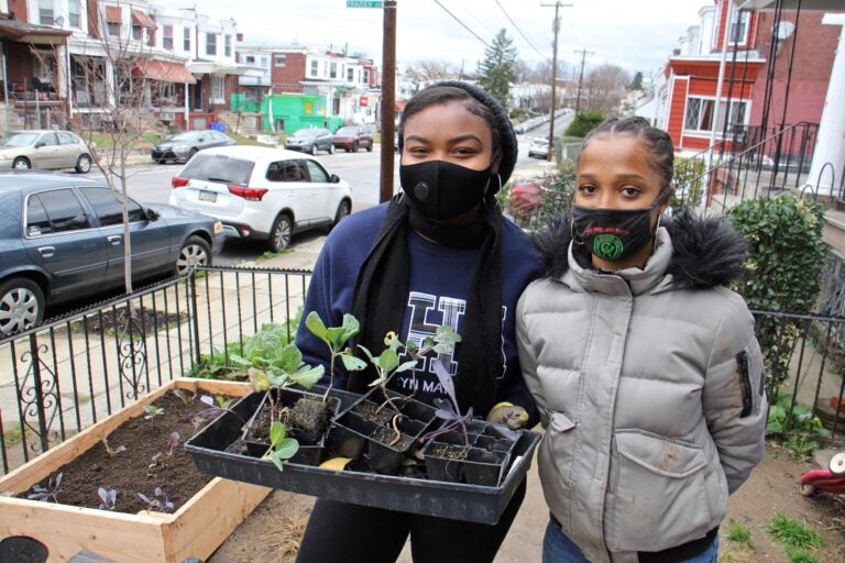 Princess Rahman (left) and Hajjah Glover finish installing a raised garden bed in Southwest Philadelphia. (Emma Lee/WHYY)