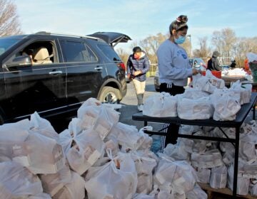 Volunteers load bags of milk for children into cars at the West Grove United Methodist Church. (Emma Lee/WHYY)