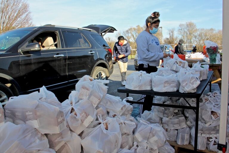 Volunteers load bags of milk for children into cars at the West Grove United Methodist Church. (Emma Lee/WHYY)