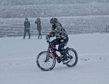 A person rides a bike during a snow storm outside the Philly Art Museum